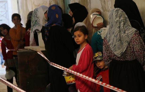 Syrians line-up waiting to receive meals distributed by the "Syria charity" NGO to impoverished families during the Muslim holy fasting month of Ramadan on June 11, 2016 in a rebel-held neighbourhood of the northern city Aleppo. (AFP/Thaer Mohammed)