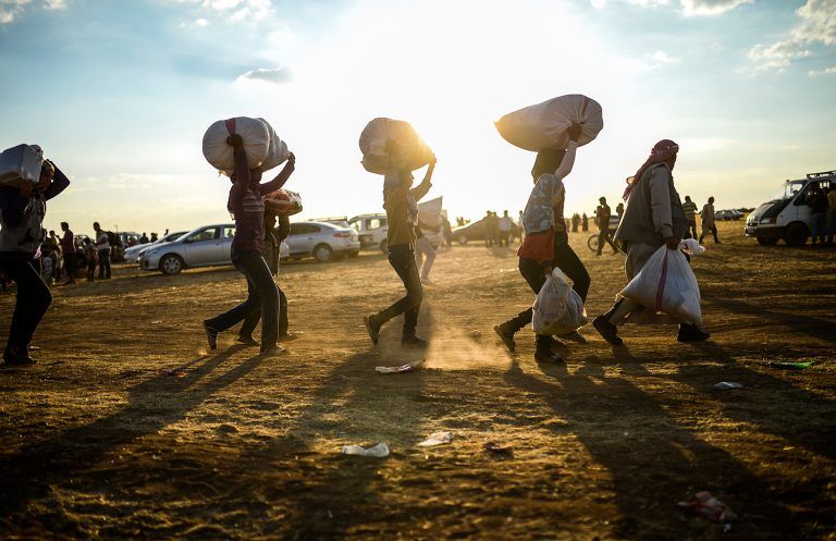 Syrian Kurds carry belongings as they cross the border between Syria and Turkey near the southeastern town of Suruc in Sanliurfa province, on September 20, 2014. Tens of thousands of Syrian Kurds flooded into Turkey on Saturday, fleeing an onslaught by the jihadist Islamic State group that prompted an appeal for international intervention. AFP PHOTO/BULENT KILIC
