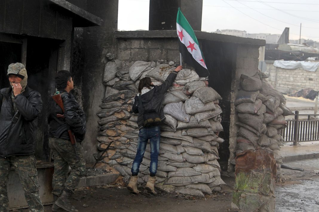 Une manifestante pour la libération des prisonniers des prisons gouvernementales syriennes dépose le drapeau de l'opposition sur un check-point contrôlé par l'Armée syrienne libre à Alep, le 24 janvier 2016.