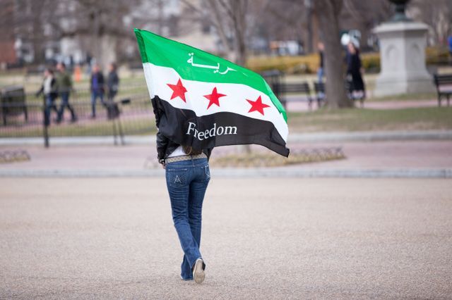 Une femme porte un drapeau pour la liberté en Syrie. 