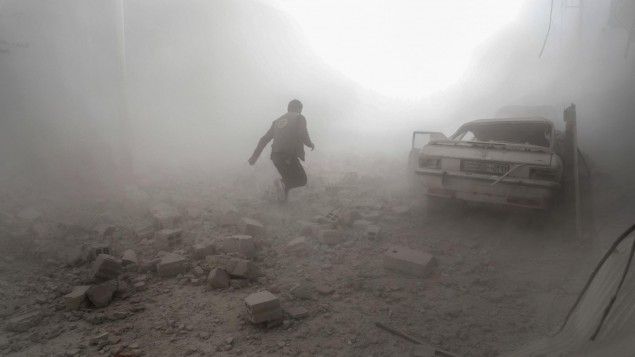Ein syrischer Weißhelm rennt durch Rauch in der Stadt Douma nahe Damaskus, die von Regimegegnern gehalten wird. (AFP / Sameer Al-Doumy)