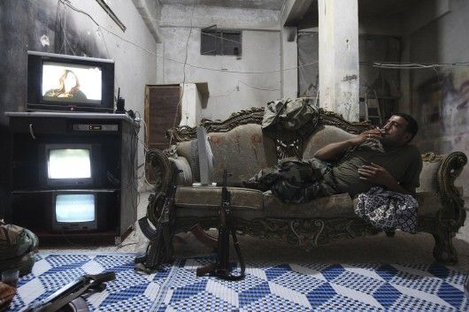 Un soldat de l'Armée syrienne libre regarde la télévision à Alep en 2013. (REUTERS/Muzaffar Salman)
