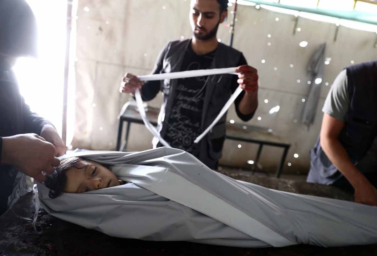 Volunteers wrap in shrouds the body of a Syrian child, Emad, 5, at a makeshift morgue following a reported air stike on the rebel-held town of Douma, east of the capital Damascus, on August 23, 2016. Volunteers wrap in shrouds the body of a Syrian child, Emad, 5, at a makeshift morgue following a reported air stike on the rebel-held town of Douma, east of the capital Damascus, on August 23, 2016.